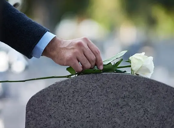 Cropped shot of a man placing a white rose on a grave