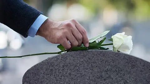 Cropped shot of a man placing a white rose on a grave